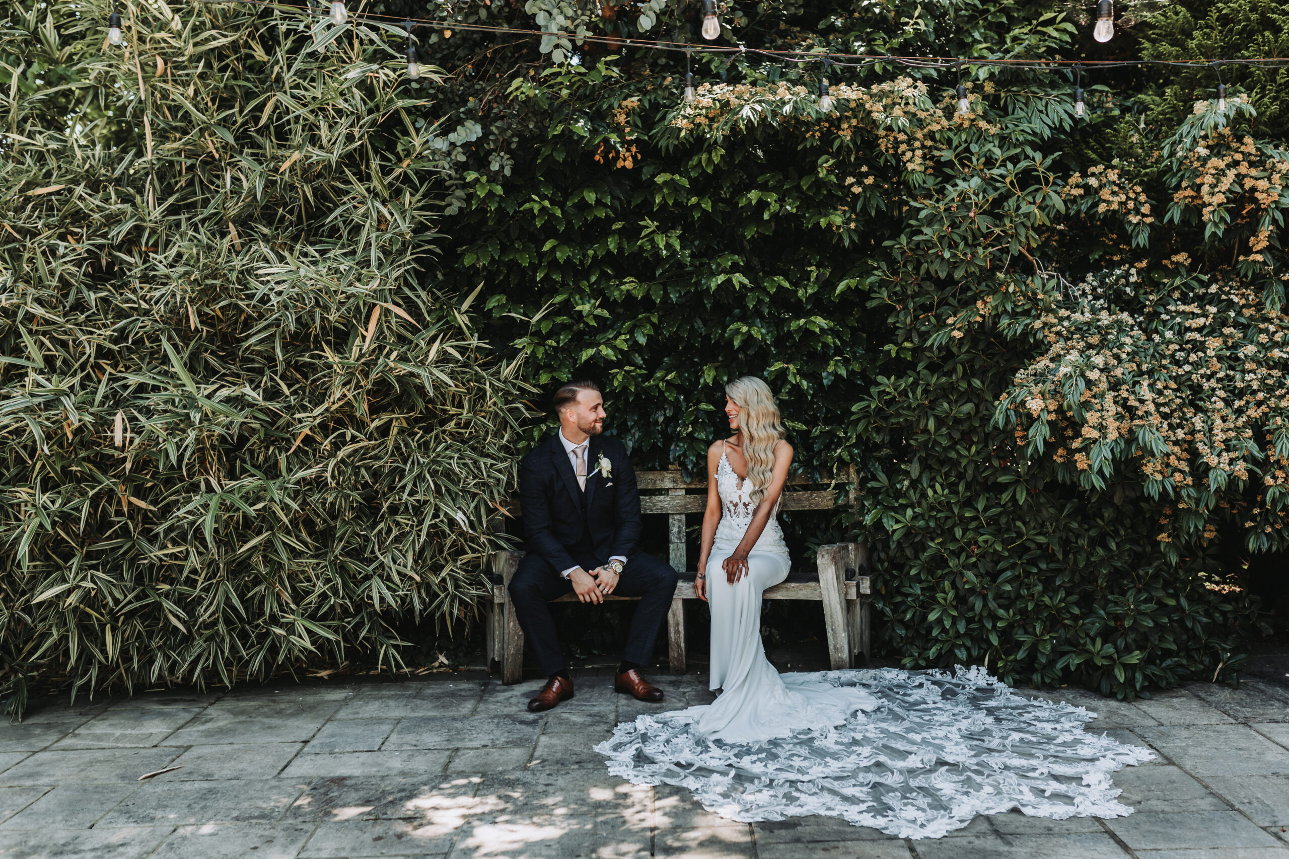 bride and groom looking at eachother on a bench