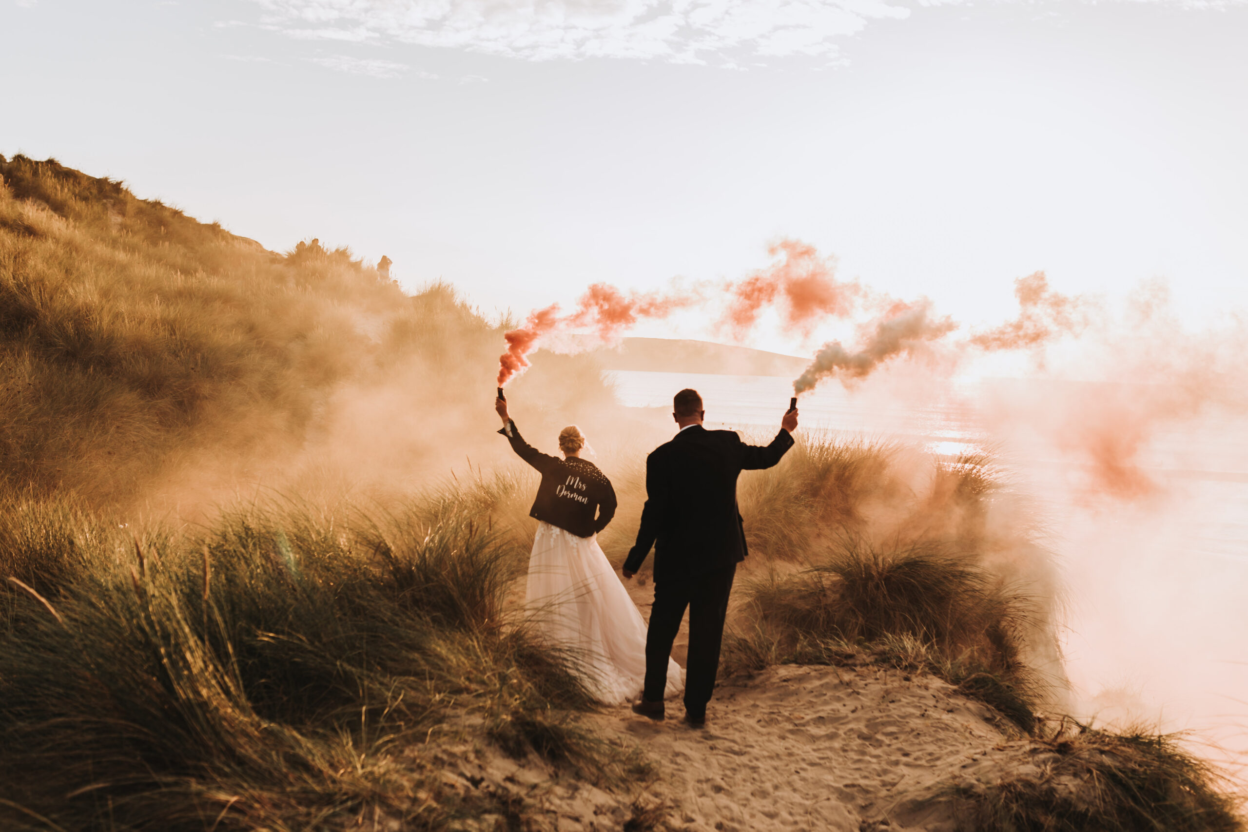 bride and groom walking with smoke bombs in cornwall