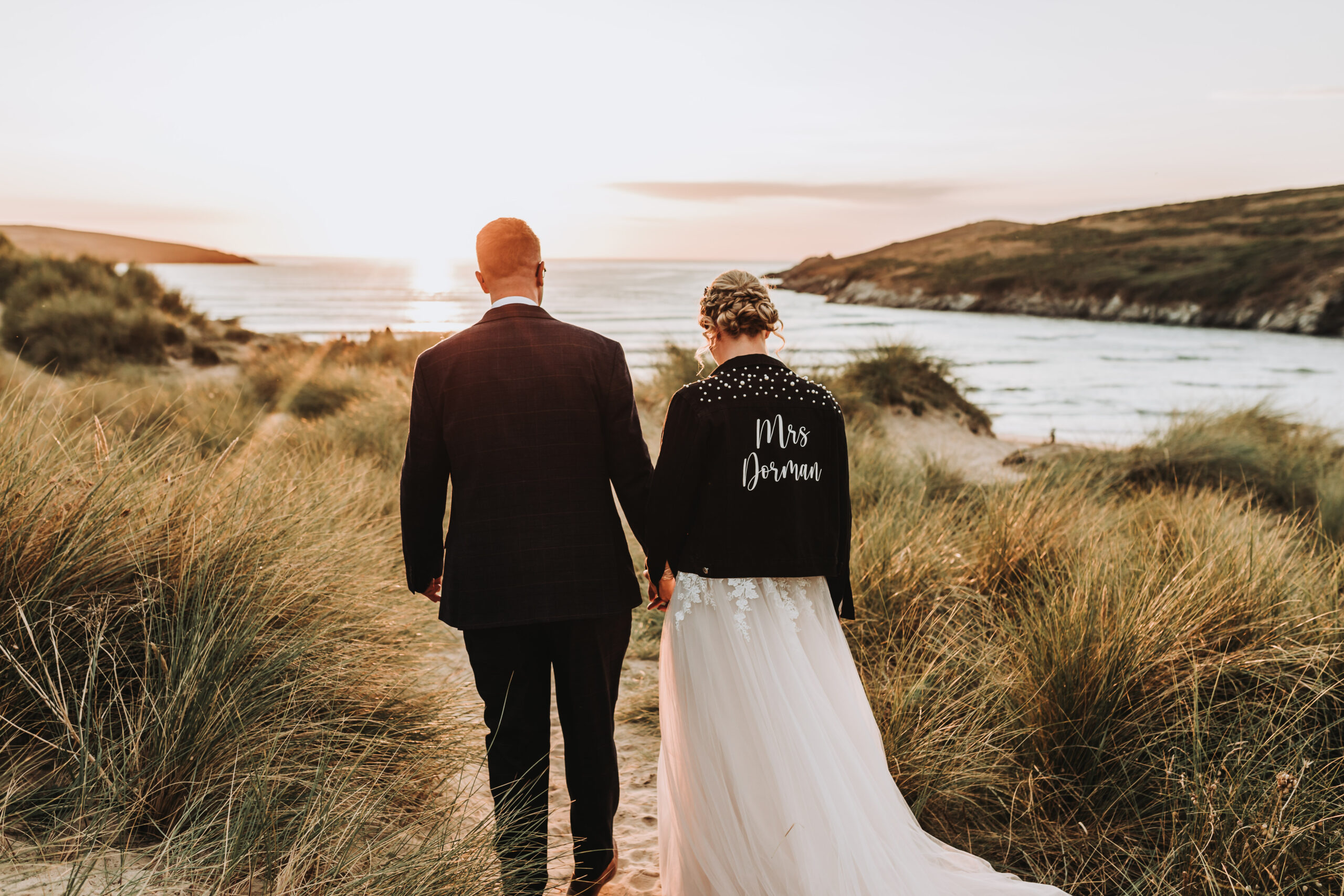 bride and groom walking through cornish sand dunes