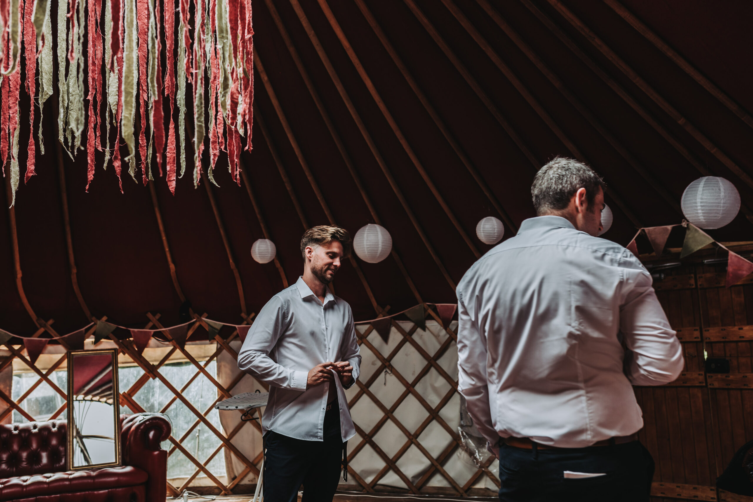 groom putting shirt on in a yurt