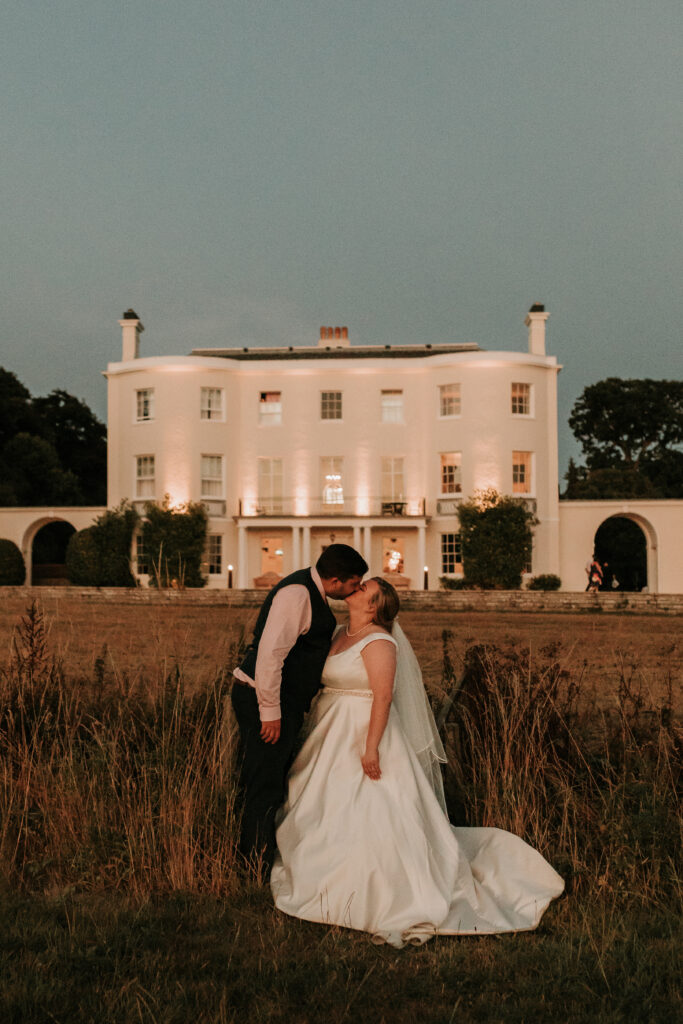 bride and groom kissing in front of rockbeare manor