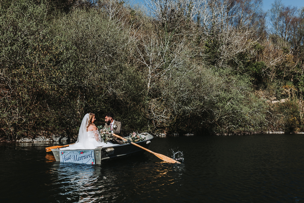 bride and groom in rowing boat at cornish tipi wedding