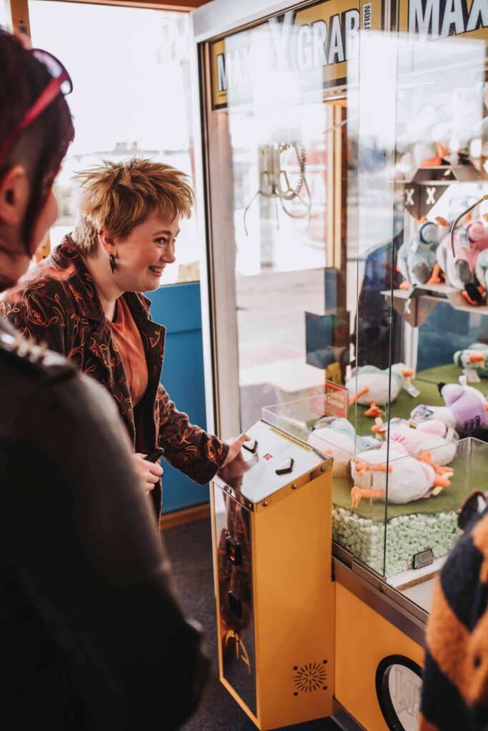 woman using a claw grabbing machine in an arcade