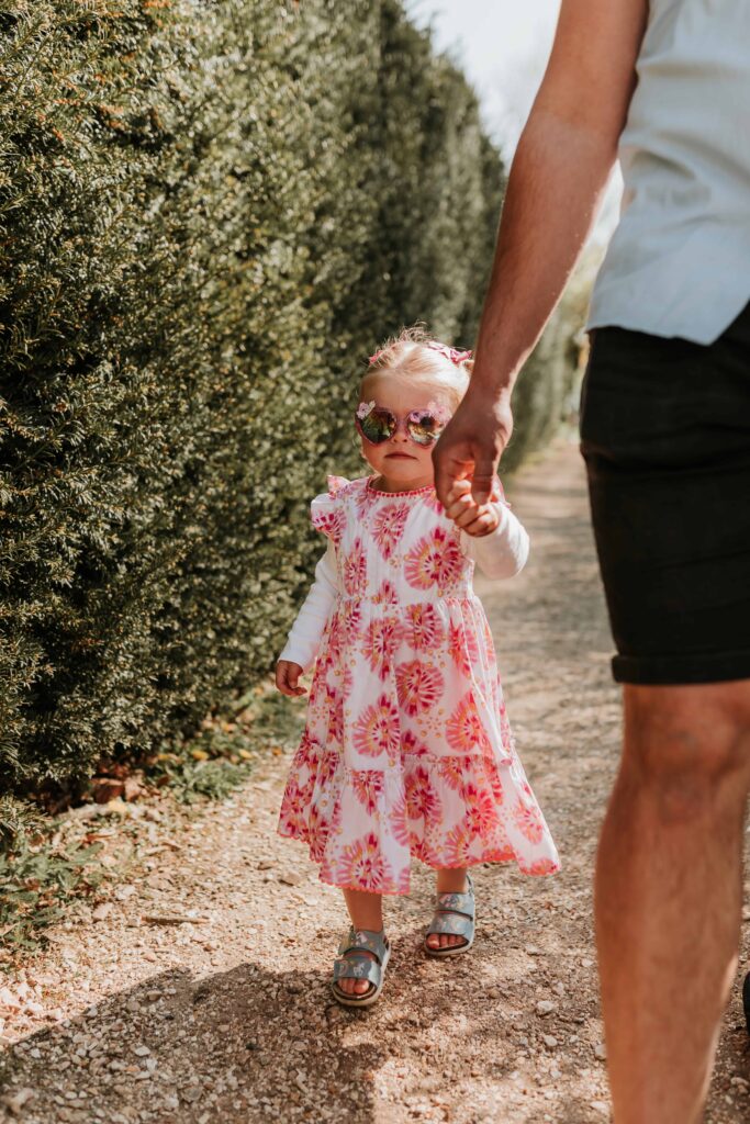 little girl holding her dads hand with sunglasses on