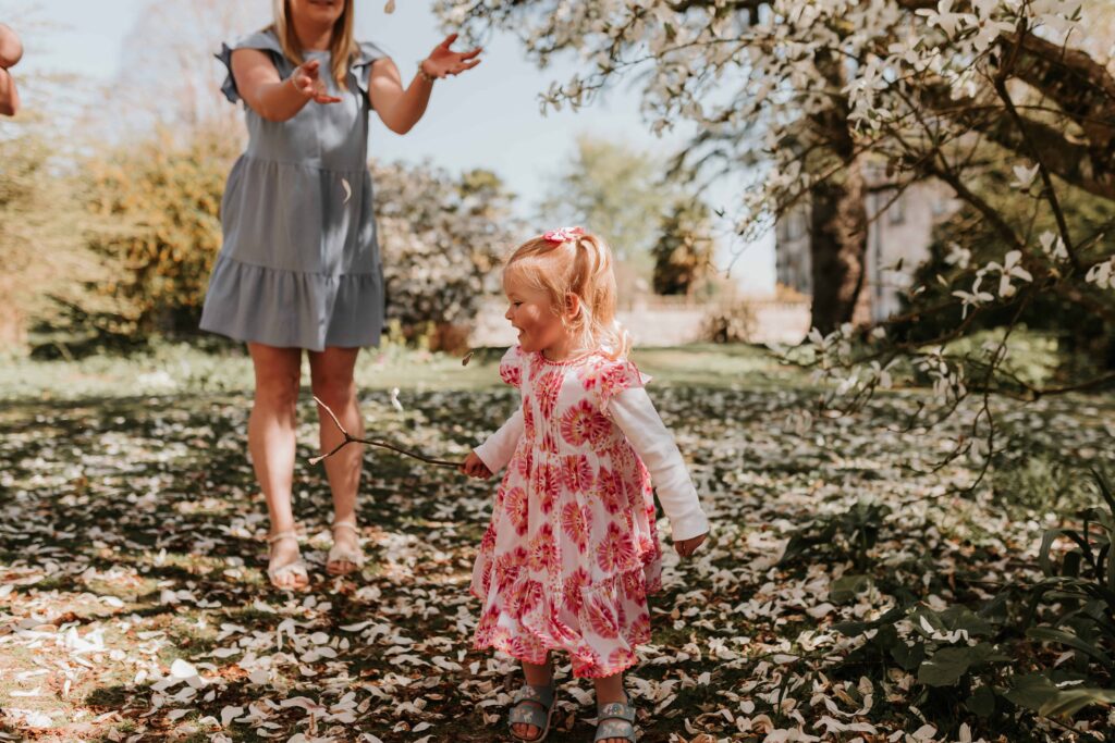 little girl smiling whilst petals rain down on her