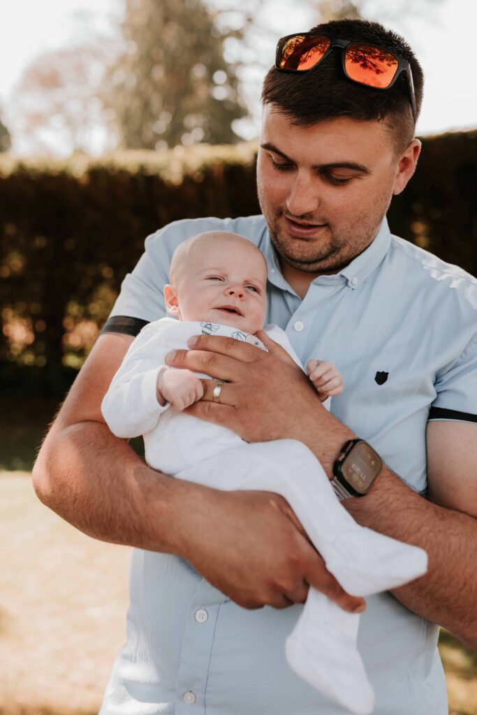dad holding baby son smiling
