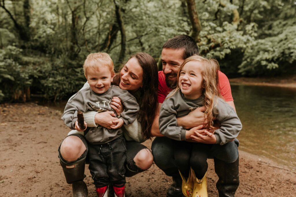 family of four cuddling and giggling mum dad son and daughter at family photoshoot in cornwall
