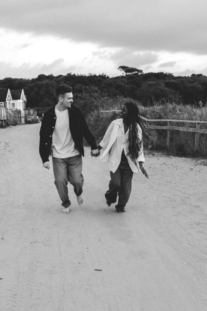 man and woman running along beach huts