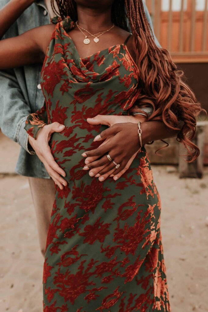 man behind woman holding his hands on her pregnant belly