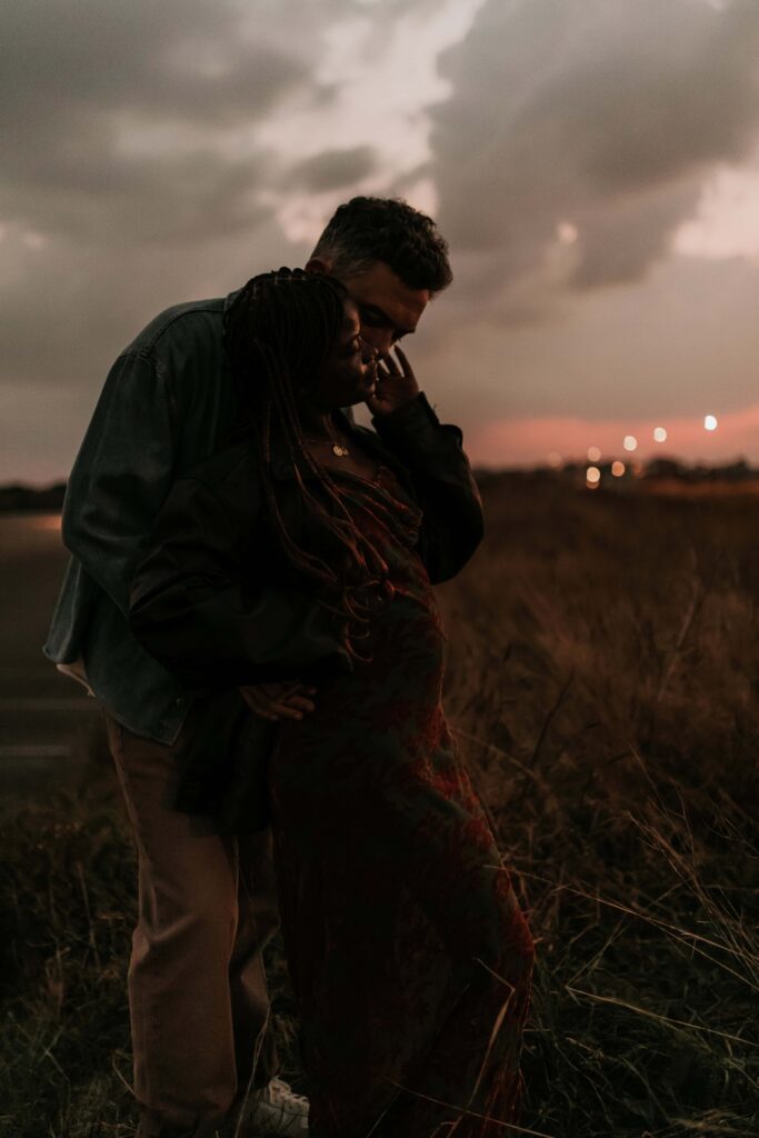 man stood behind wife in the dark as the sun sets at maternity & newborn photoshoot