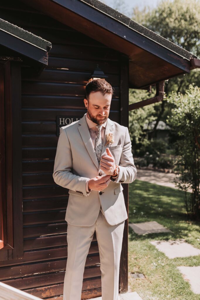 groom adjusting sleeves outside lodge at chycara wedding