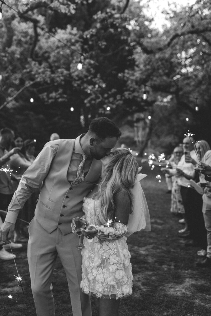 bride and groom kissing at sparkler exit