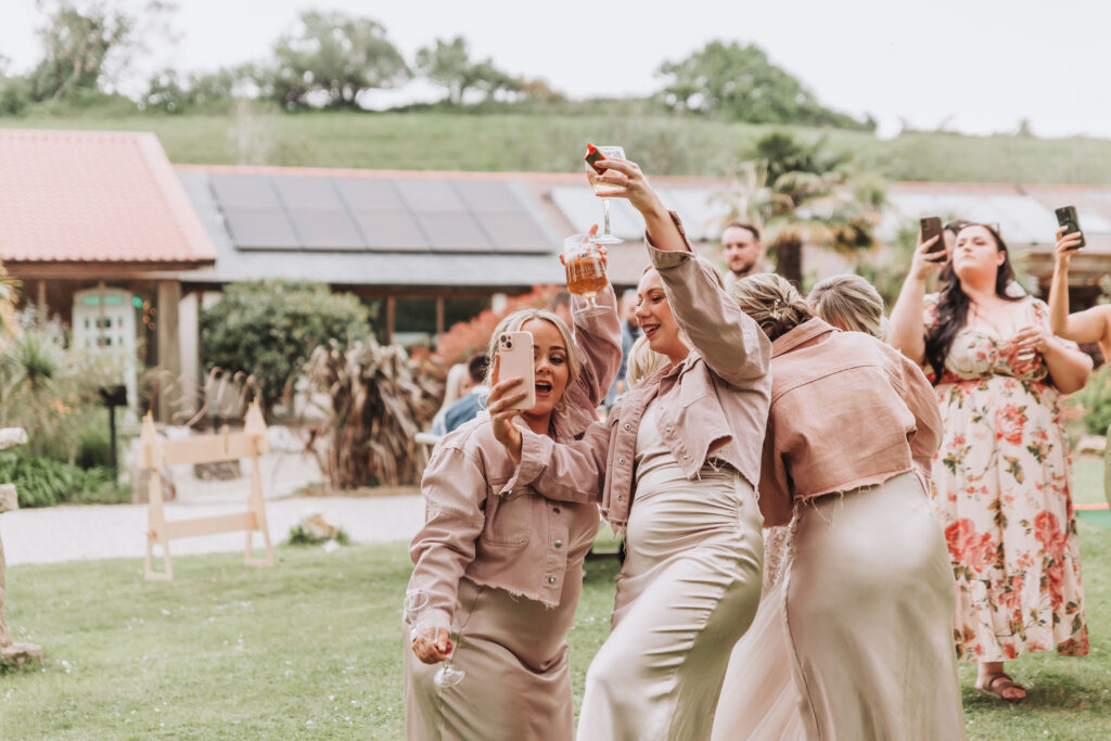 bridesmaids dancing and taking selfies outside chycara in cornwall