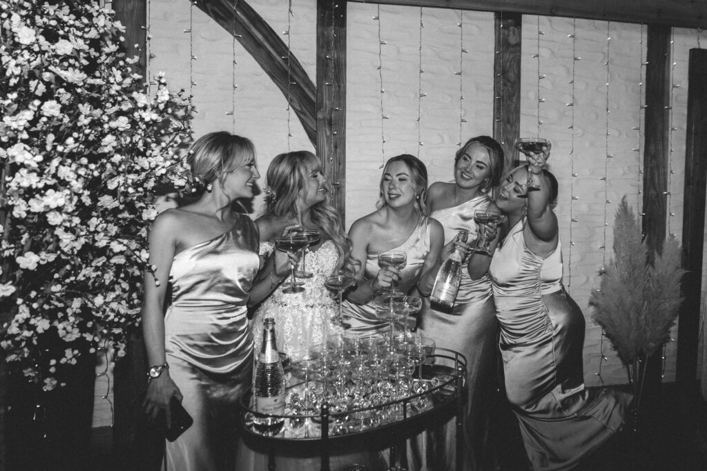 bridesmaids smiling with eachother by champagne tower