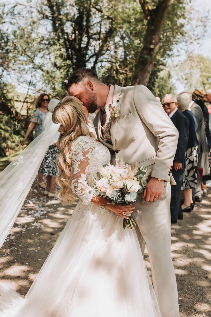 bride and groom kissing at end of confetti aisle