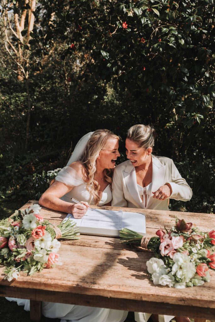 two brides laughing signing the register photo by lgbtq+ wedding photographer
