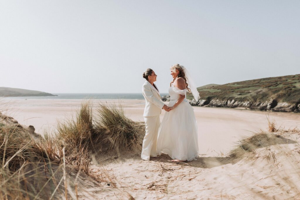 two brides holding hands on top of cornish sand dune