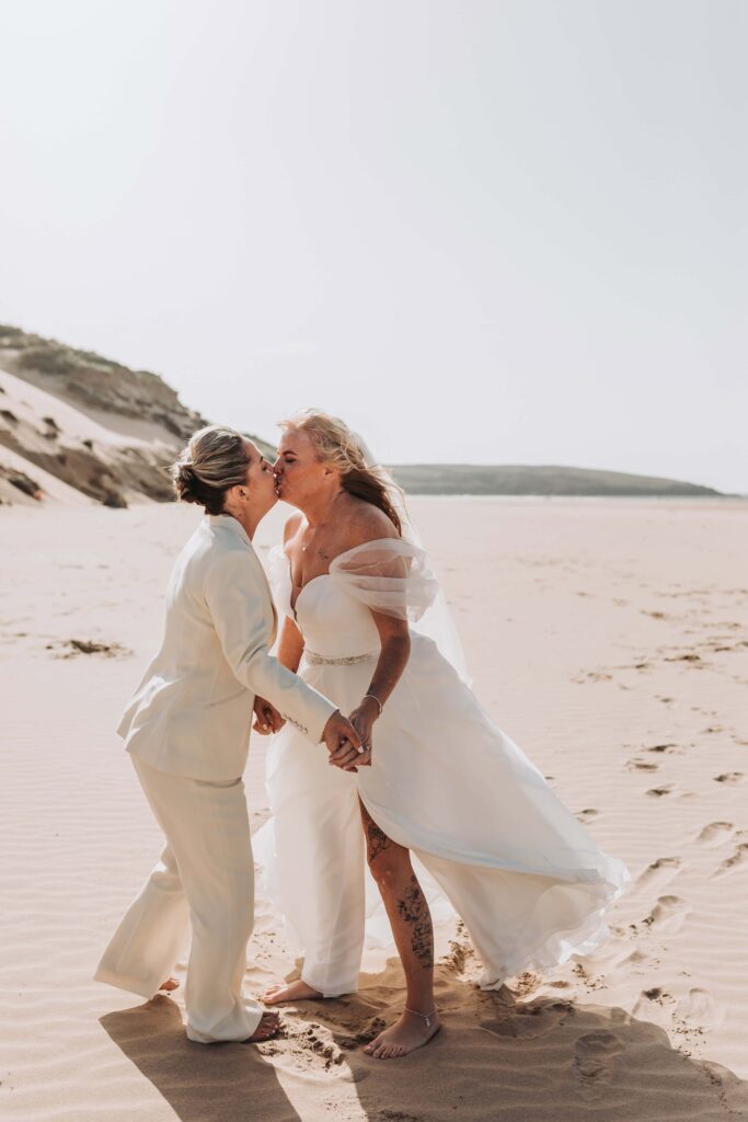 two brides kissing on cornish beach