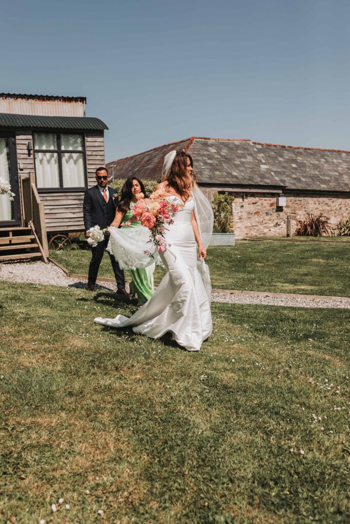 bride walking with bridesmaids holding veil