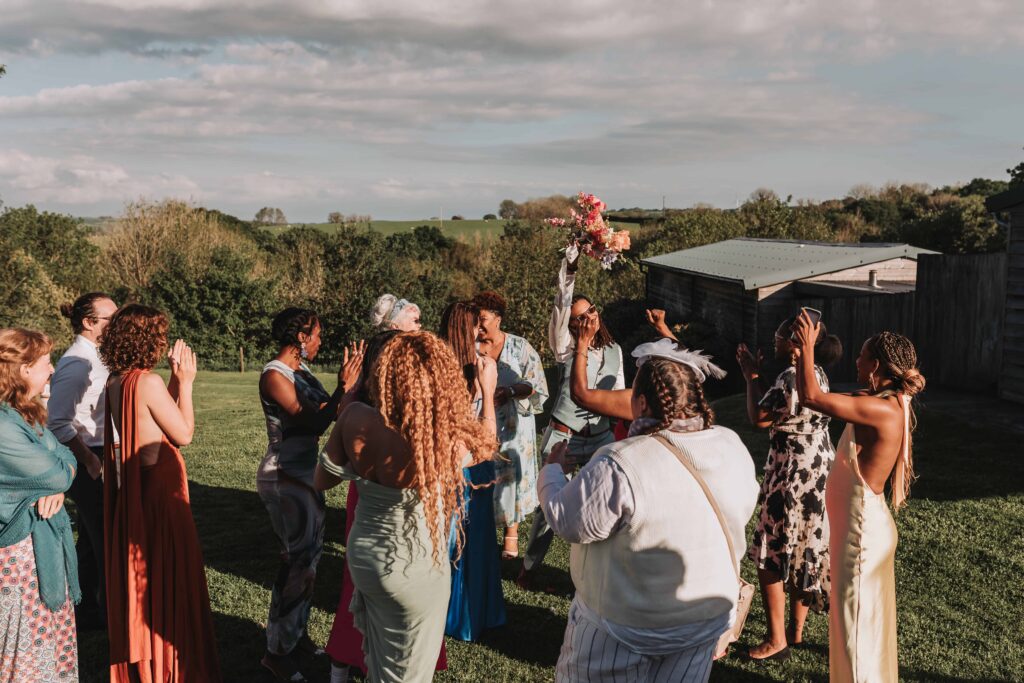 guest holding thrown bouquet in the air at the green cornwall
