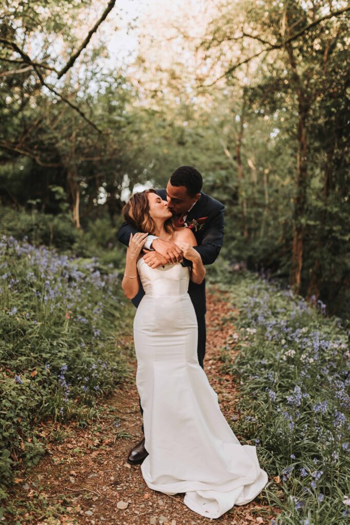 bride and groom kissing in bluebell field at the green cornwall