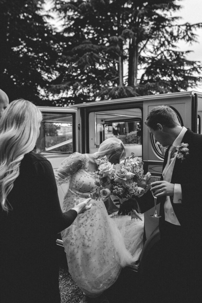 groom helping bride out of car at coombe lodge wedding