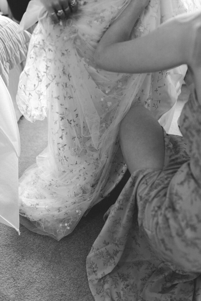 bride having her dress put on by bridesmaid