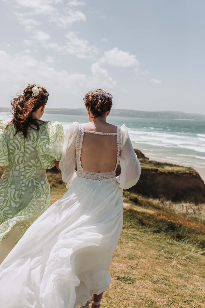 brides walking along cornish coastline