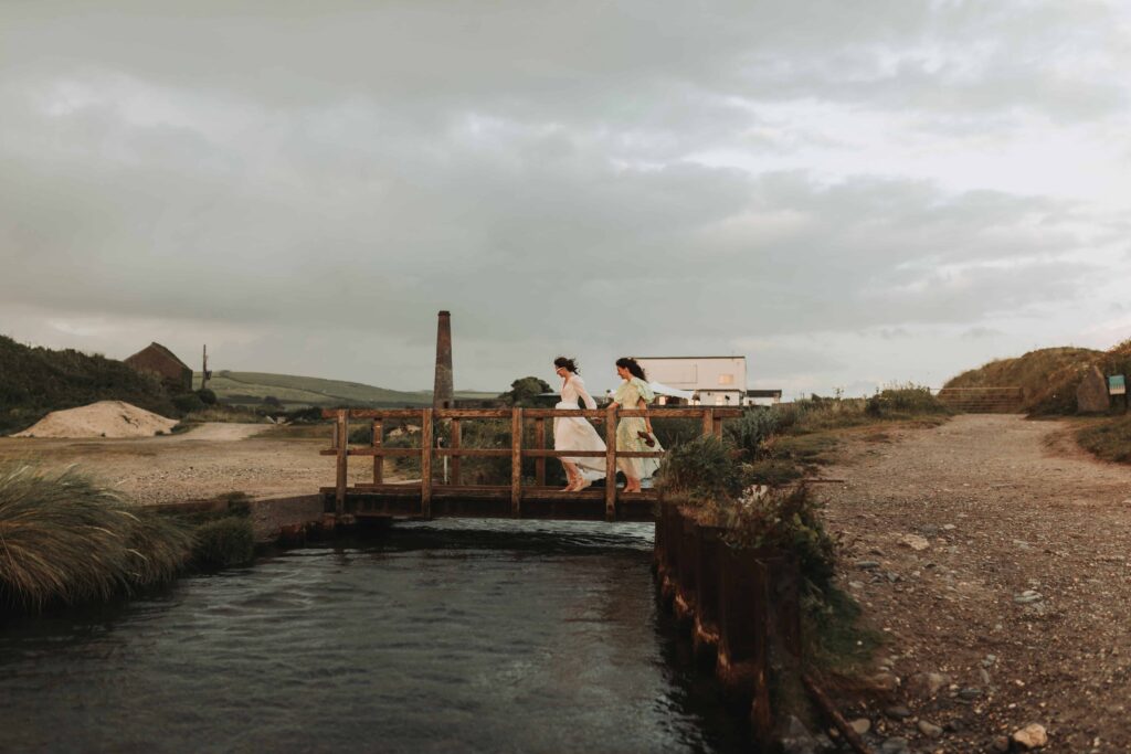 brides crossing a bridge on a beach