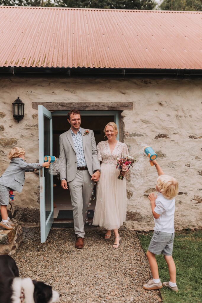 bride and groom officially married with sons blowing bubble guns