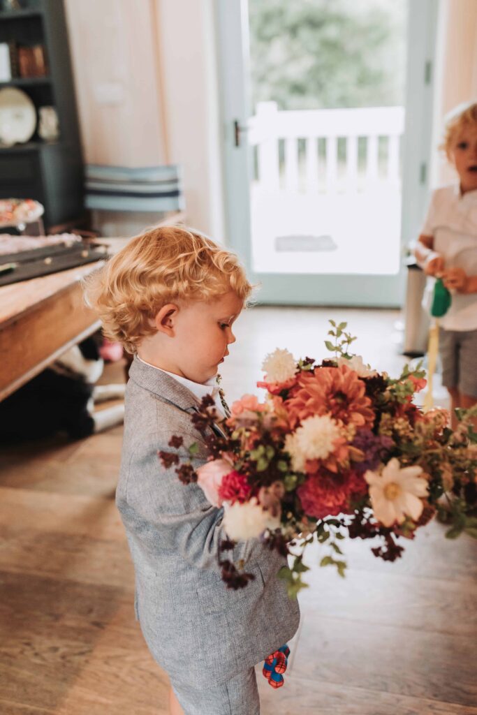 young boy holding mums bouquet of flowers