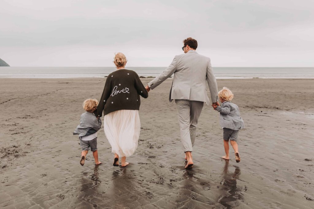family of four walking towards the sea on wedding day