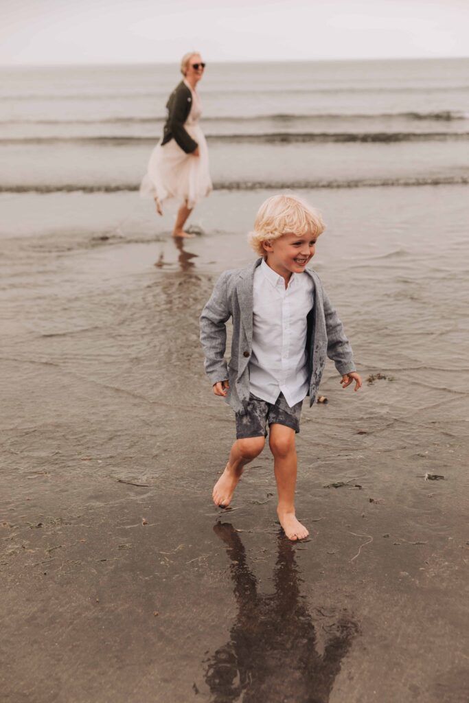 young boy running around the beach in suit