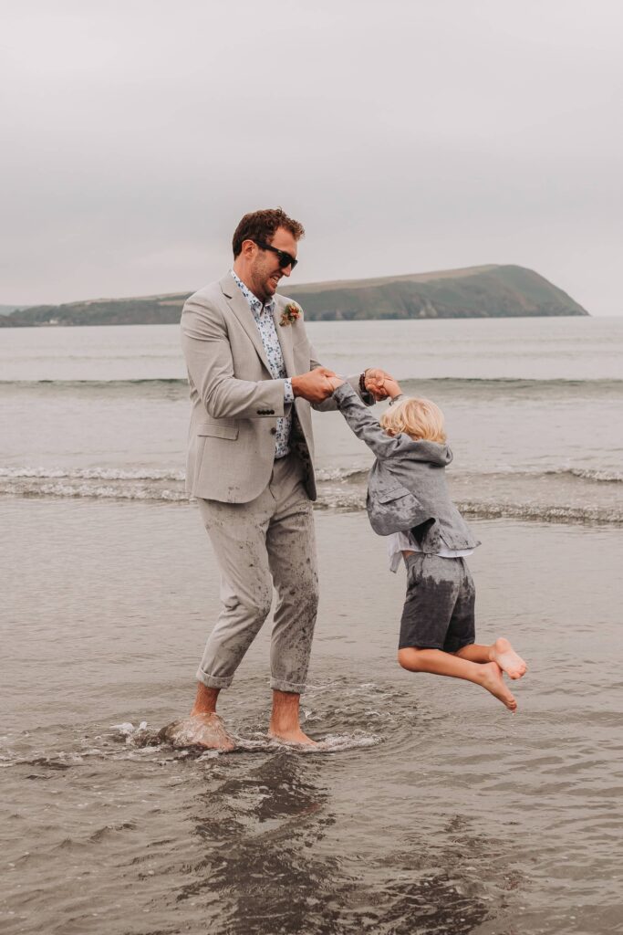 groom spinning his son around in the sea