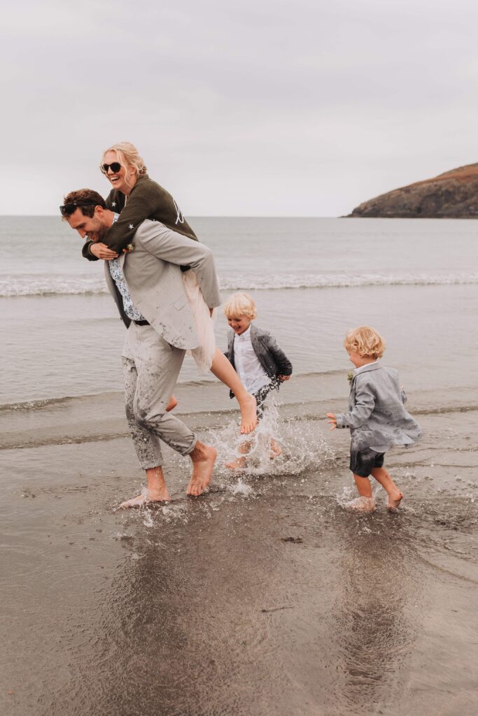 bride and groom being chased by sons along the beach