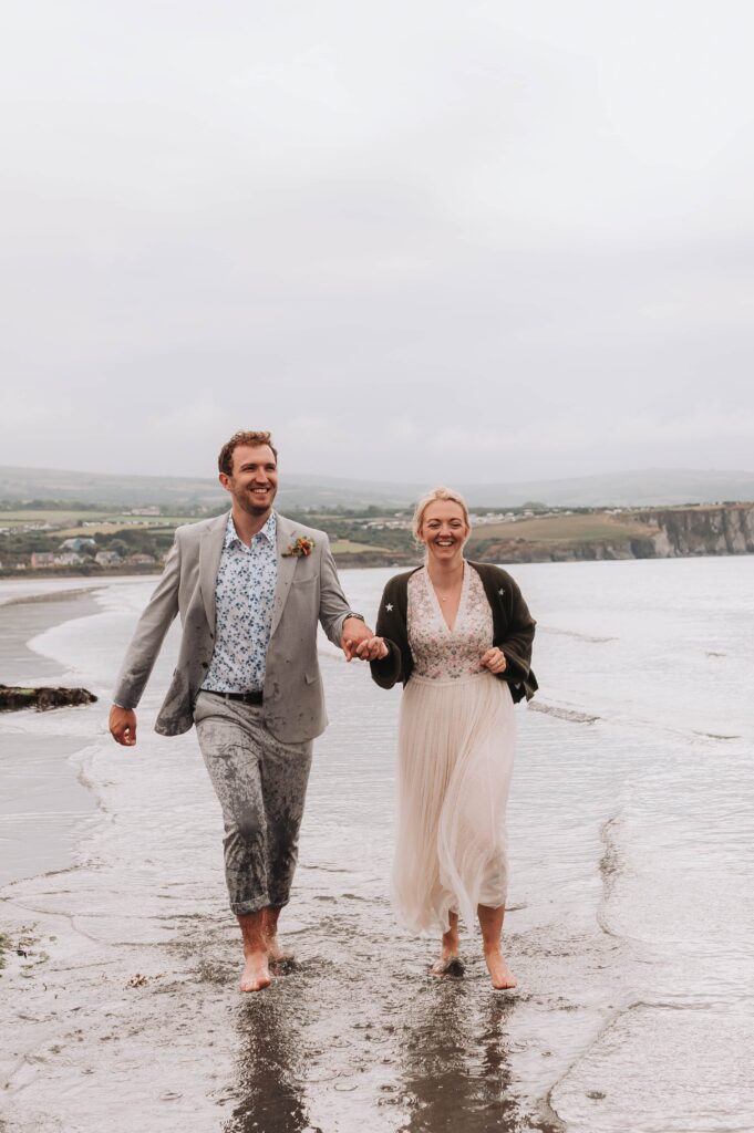 bride and groom running along the beach smiling