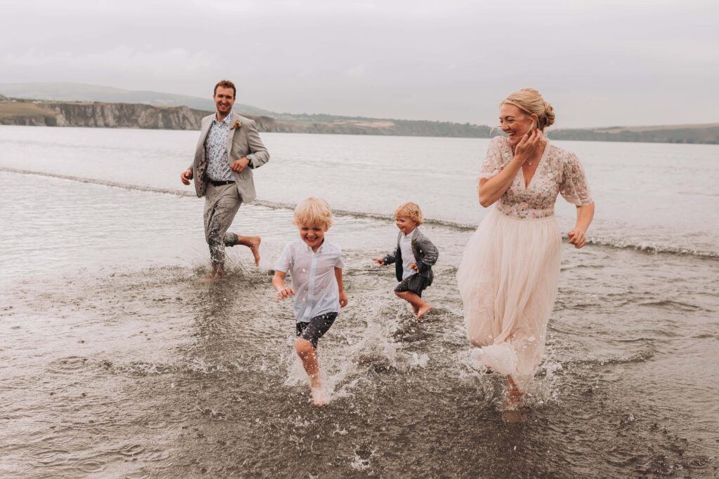 family of four running through the waves at elopement