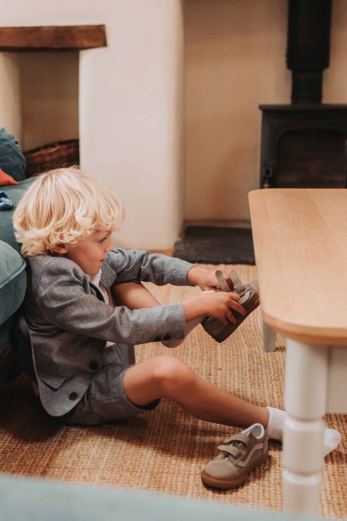 young boy putting on shoes for wedding day