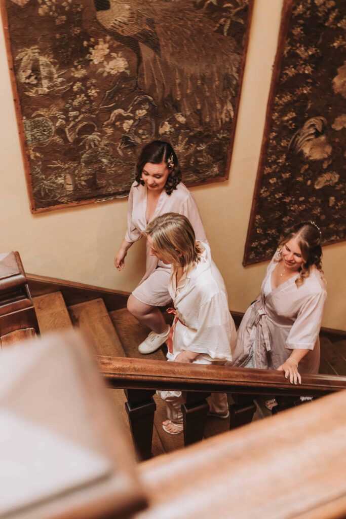 bride and bridesmaids walking up stairs at wadhurst castle wedding