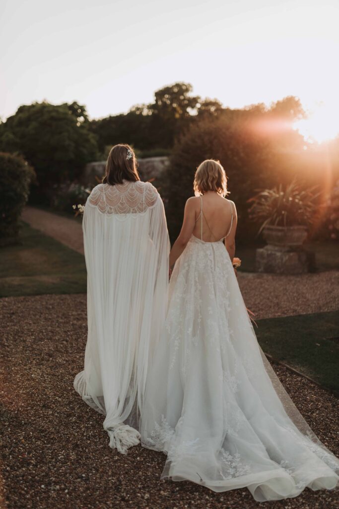 two brides walking hand in hand in the sunset