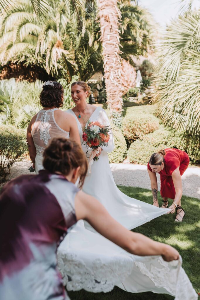 two brides having their trains straightened out