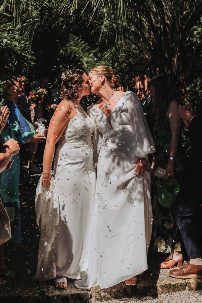 brides kissing under confetti at cornwall lgbtq+ wedding