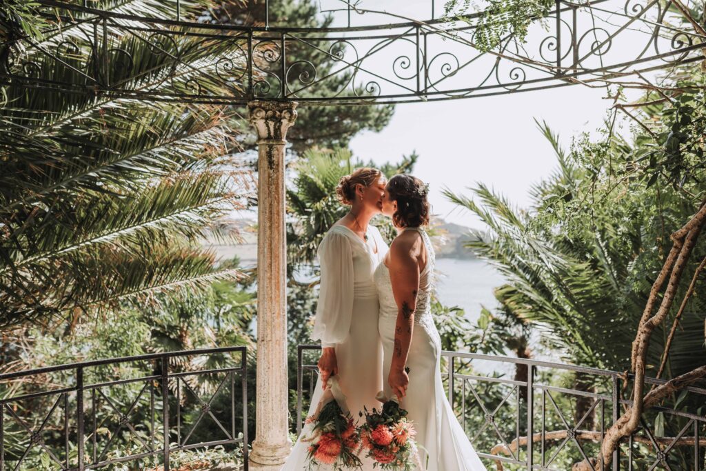 two brides kissing in lamorran gardens bird cage