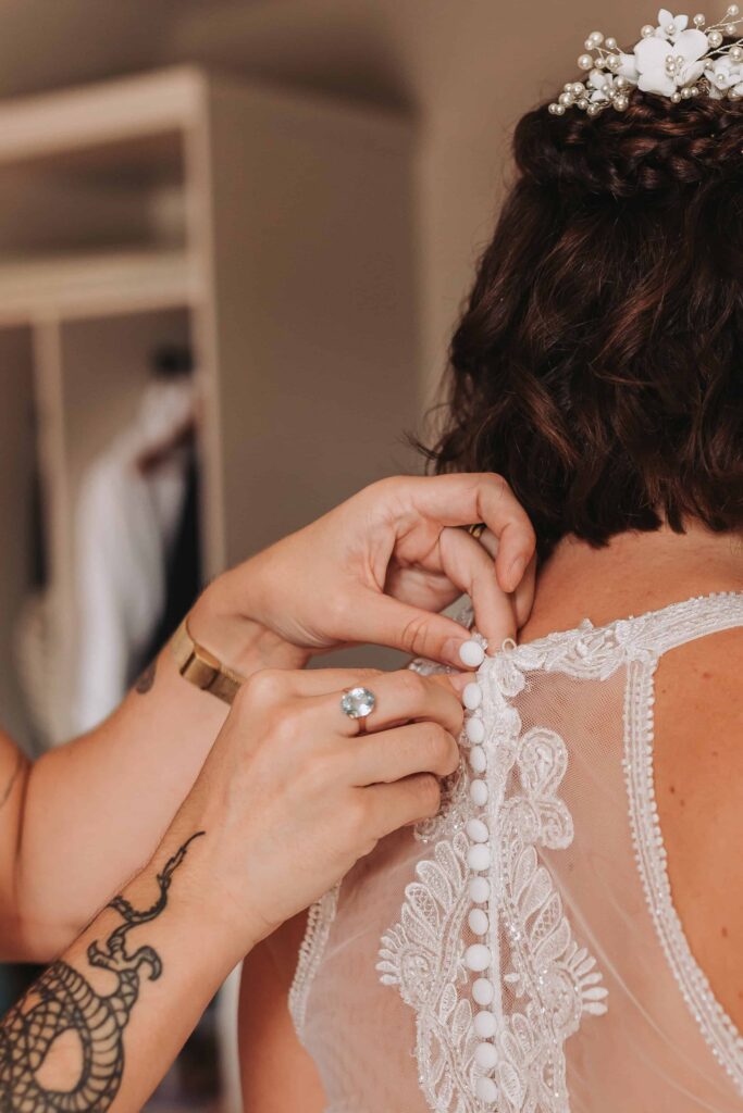 bride having her dress buttoned up at cornwall lgbtq+ wedding