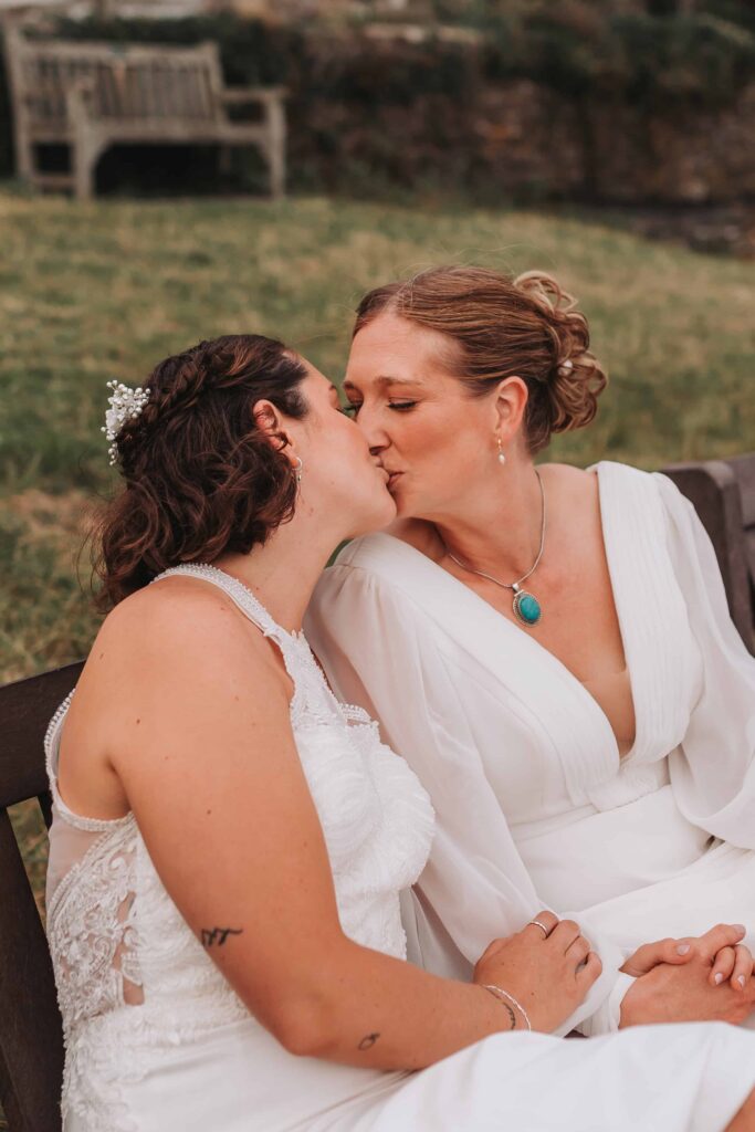 two brides kissing sitting on bench in st mawes