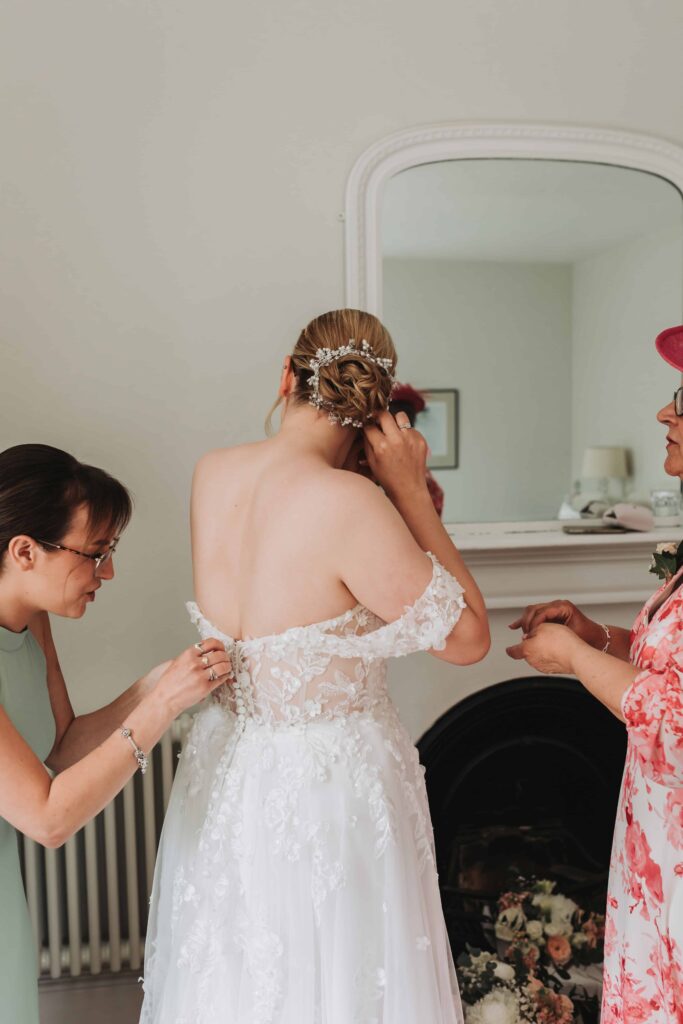 bride with her mum and sister putting jewellery and dress on