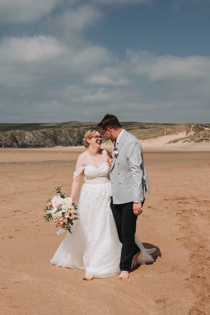 bride and groom laughing on wedding day at the beach