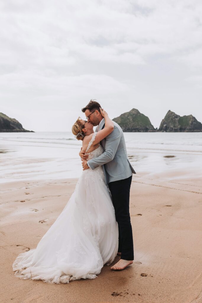 bride and groom kissing barefoot on the beach