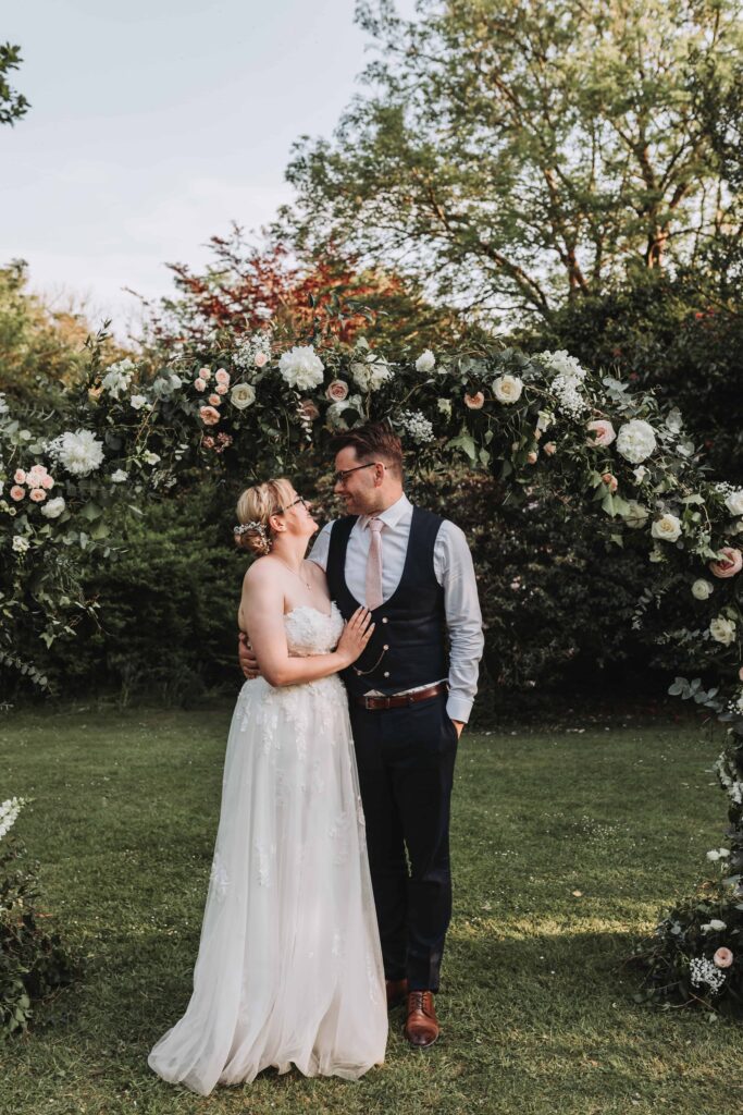 married couple looking at eachother under flower arch