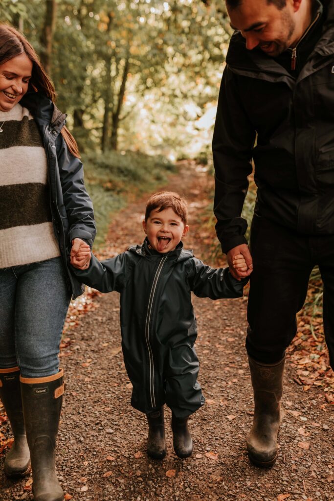 mum and dad holding sons hand whilst he sticks his tongue out
